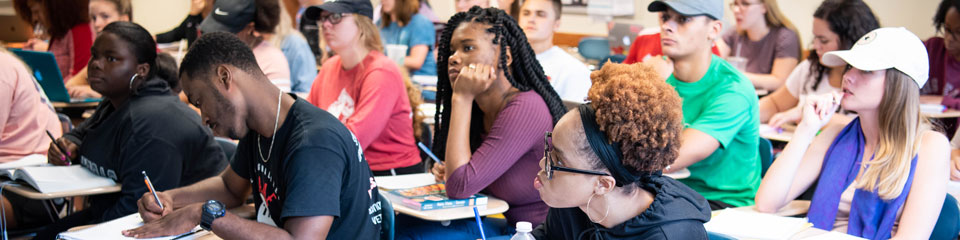 Students in a classroom sitting at desks, taking notes.