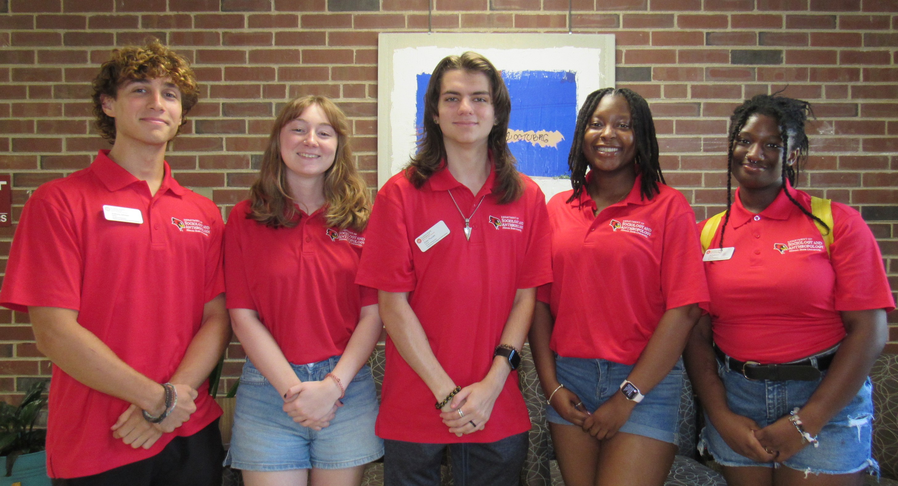 A group of people standing in front of a brick wall